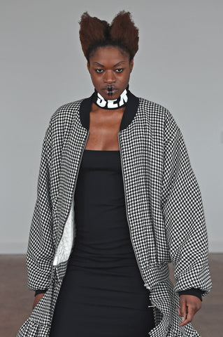 LULA LAORA AW21 Getty Images,black dress with sex necklace collar, model wears a houndstooth long bomber coat. 