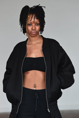 LULA LAORA AW21 Getty Images, womenswear model wears black bralette top, joggers/sweatpants with a white lady print, and a black bomber jacket.