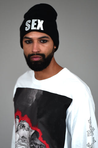 LULA LAORA AW21 Getty Images, black beanie with sex written on it. Model wears long sleeved white t-shirt with graphic print in black, white and red. 