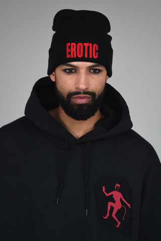 LULA LAORA AW21 Getty Images, menswear model wears a black beanie with the words erotic in red. the hoodie is black with a Red Devil lady logo.