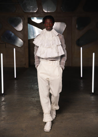 Lula Laora runway Getty, ruffled top white, mesh menswear, white high waisted trousers