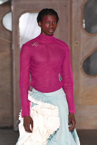 Lula Laora runway Getty pink eyebrows, mesh long sleeved fuchsia top with a high neck and embroidered beetles. aqua, light blue and white ruffled skirt. 