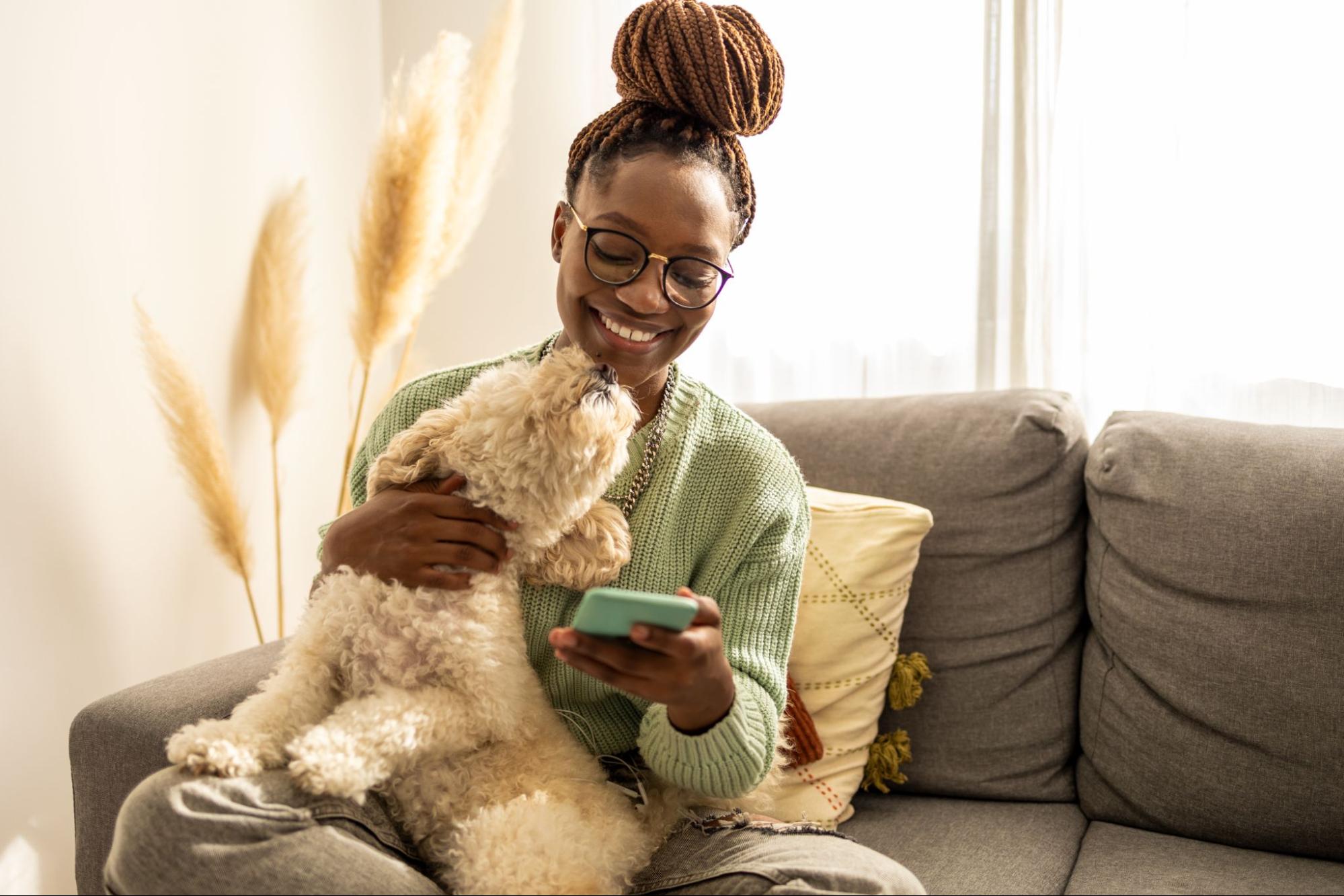 woman on the couch petting a small white dog