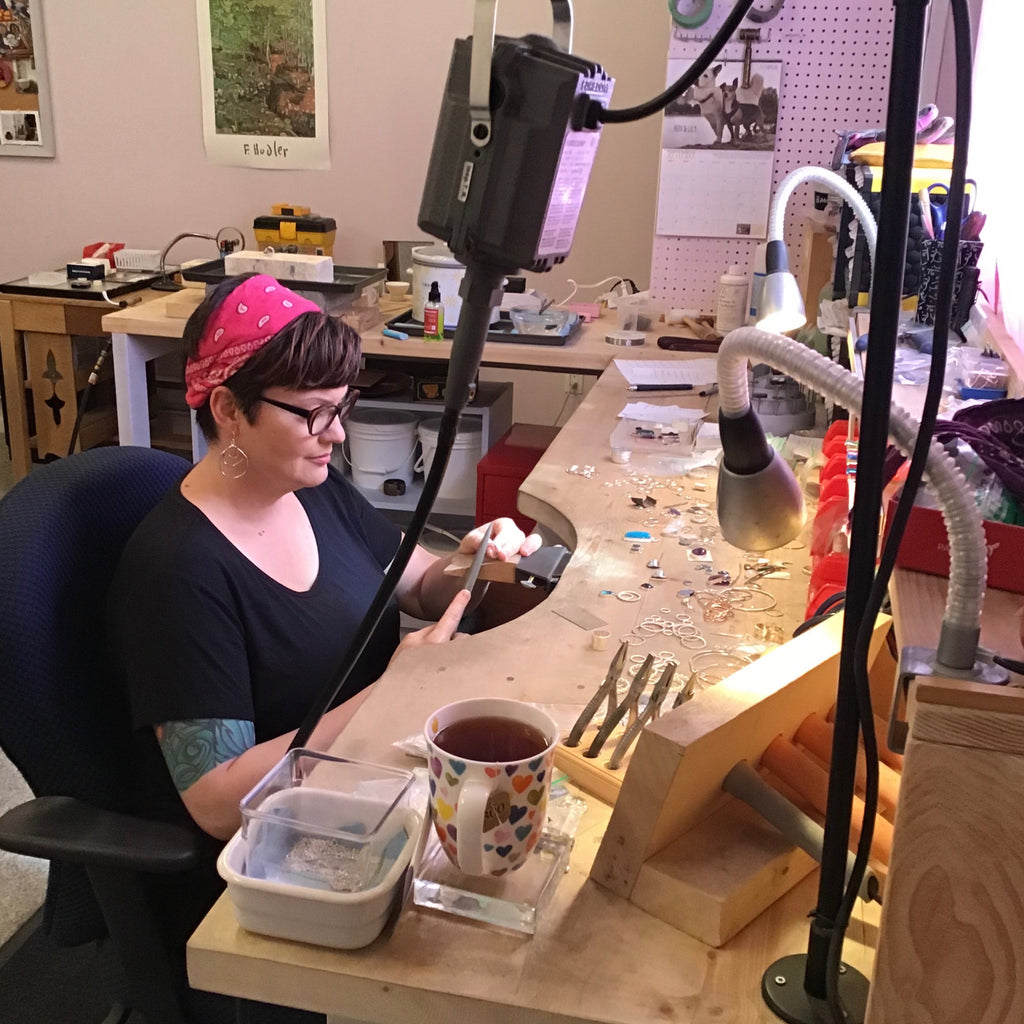 Inside a jeweler's studio virtual tour.  Mikel from Mikel Grant Jewellery sitting at jeweler's workbench.  In Sechelt, BC, Canada.