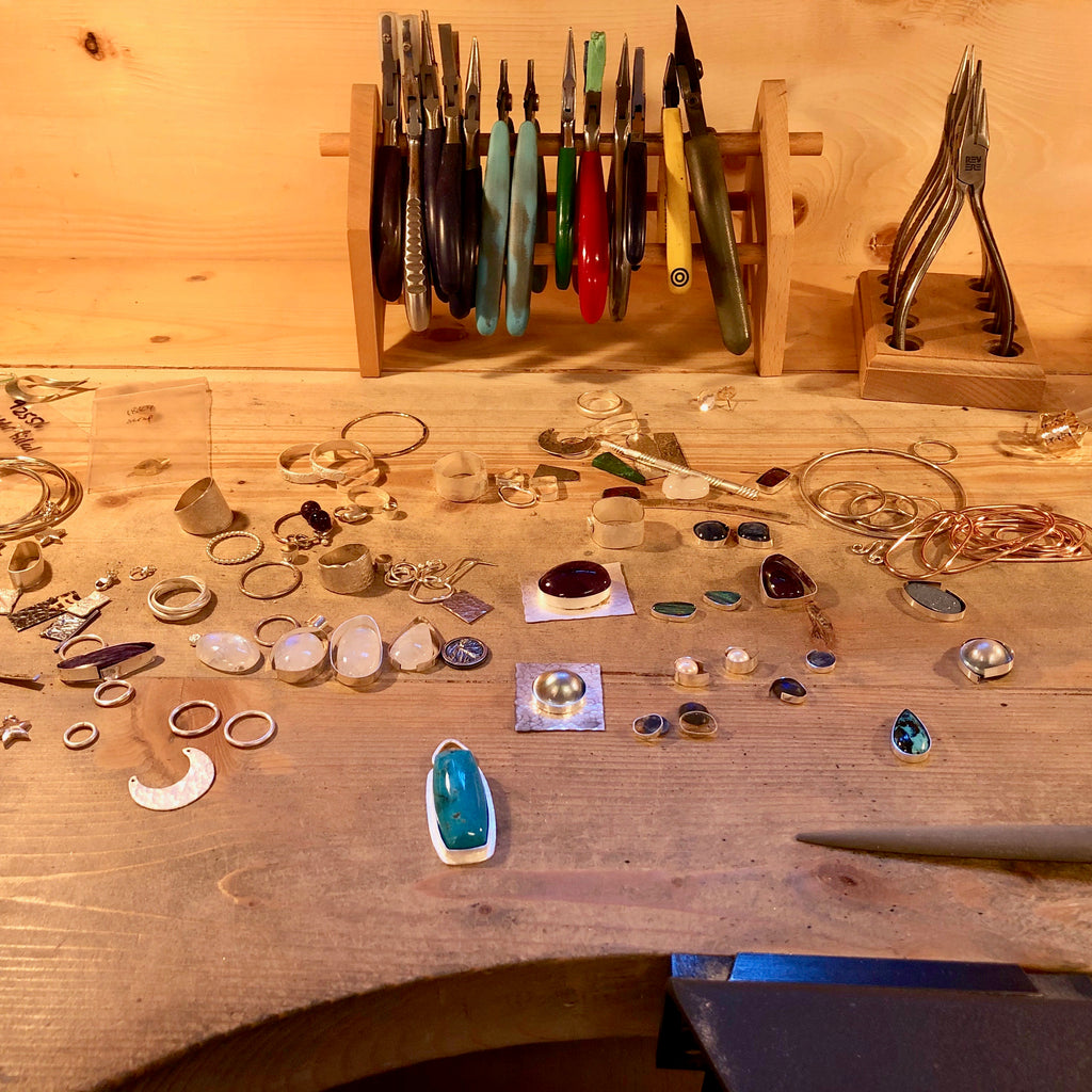 Surface d'établi à bijoux Mikel Grant avec métal et pierres précieuses.