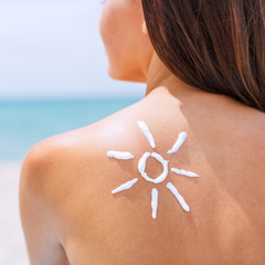 Frau mit Sonnenschutz in Form einer Sonne am Strand