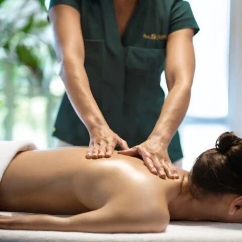 A massage therapist working on a client's back in a tranquil spa.