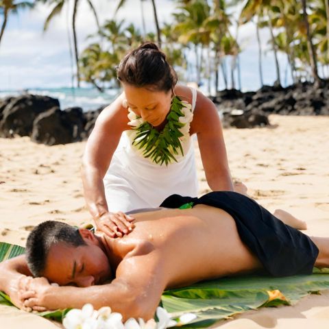 A massage practitioner performing Lomi Lomi massage on a Hawaiian beach.