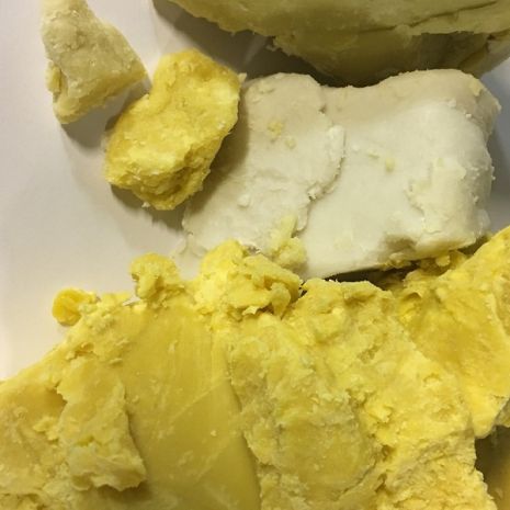 photo of refined and unrefined shea butter. Refined shea butter is white while unrefined is yellow.