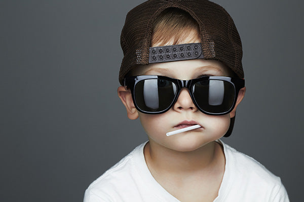 Funny Young Boy Eating A Lollipop. Child in sunglasses