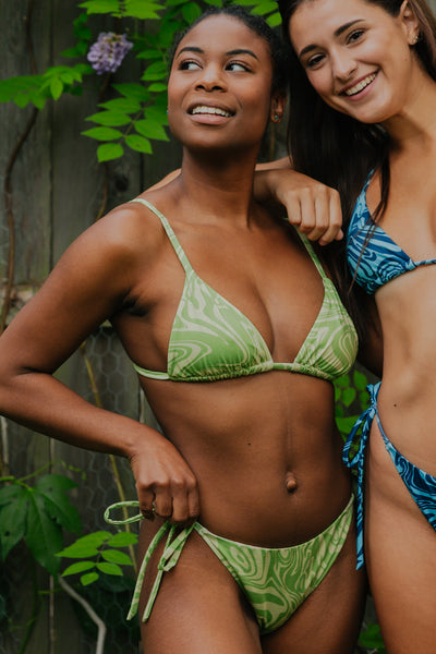 Two models smiling and wearing string bikinis with marble prints.