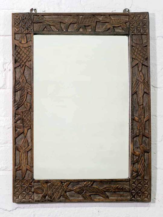 A rustic Indian wooden mirror with carved animals running around the frame.