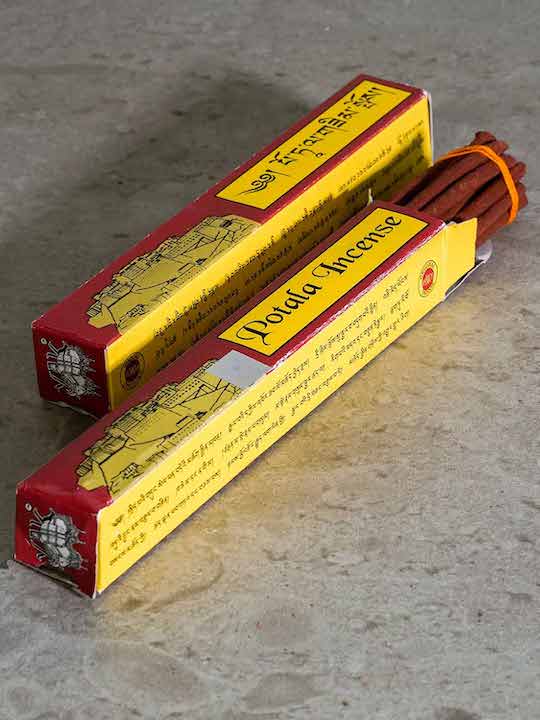 Tibetan incense in a maroon and yellow packet with a drawing of the Potala Palace. 