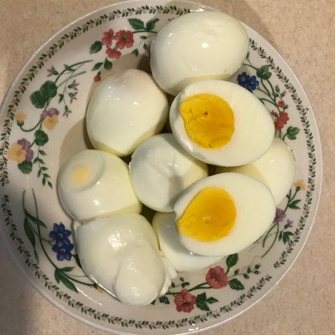 hard boiled eggs in a bowl, one is cut in half and has a solid bright yellow yolk