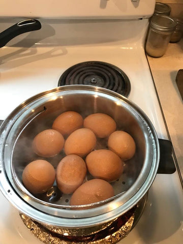 brown eggs in a stainless steel steamer on an electric stove