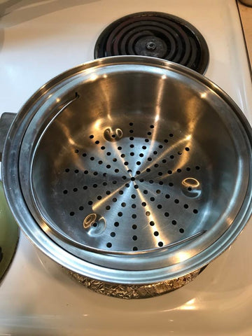stainless steel steamer basket in a pot on an electric stove