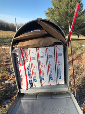 a large metal mailbox with door open and flag up is full of small boxes and padded envelopes