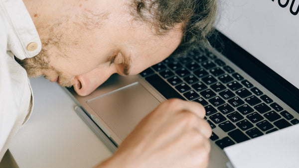 Man feeling exhausted with head laying on laptop 