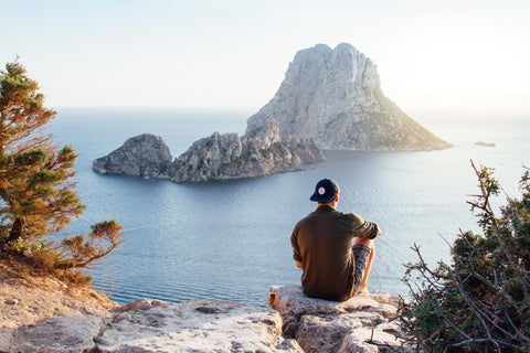 man relaxing outdoors with a view of the water and taking advantage of the benefits of ashwagandha for stress relief and relaxation