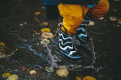 A child splashes in a puddle - Snail Mail Stories encourages children to connect with nature