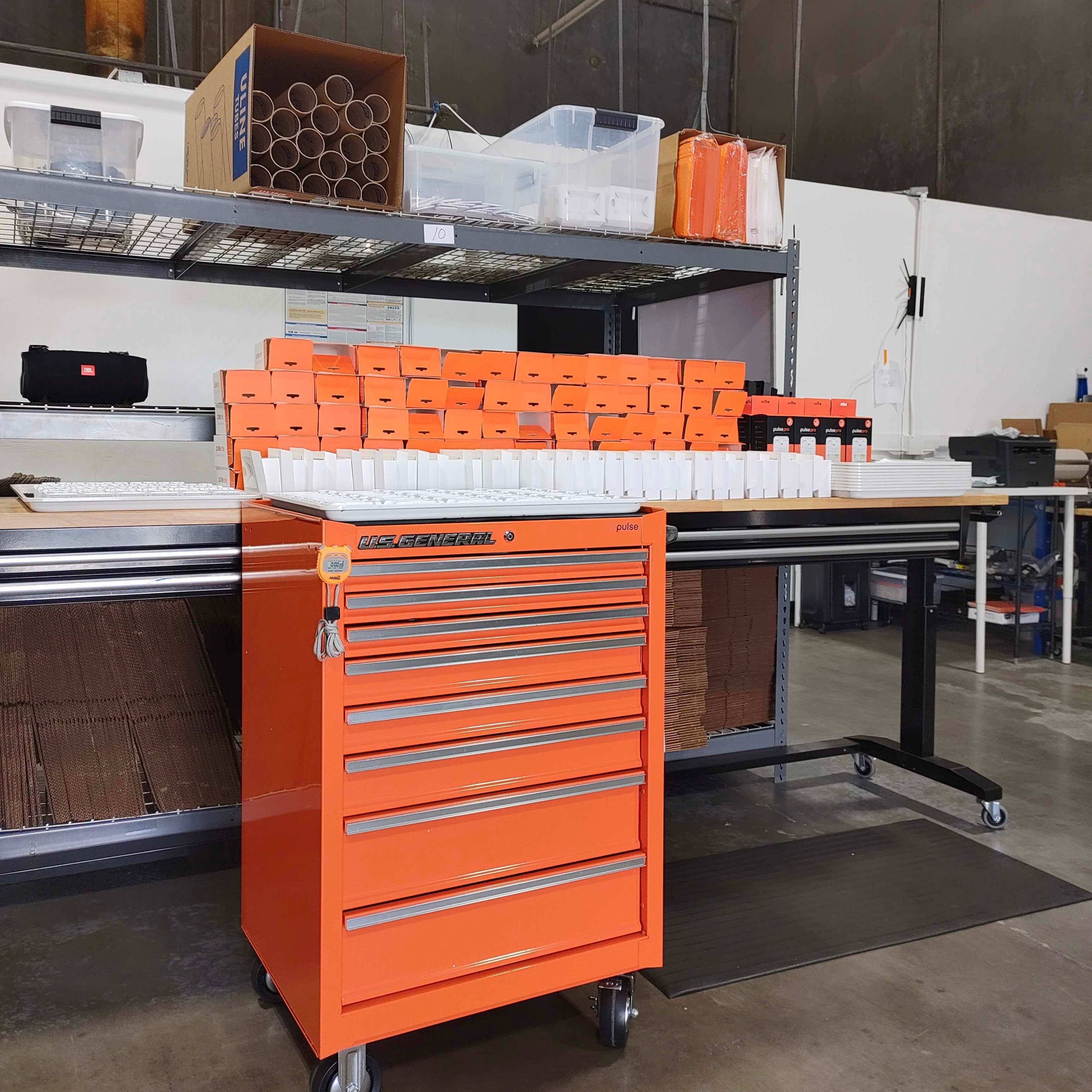 Front view of a bright orange toolbox and table with product boxes stacked up