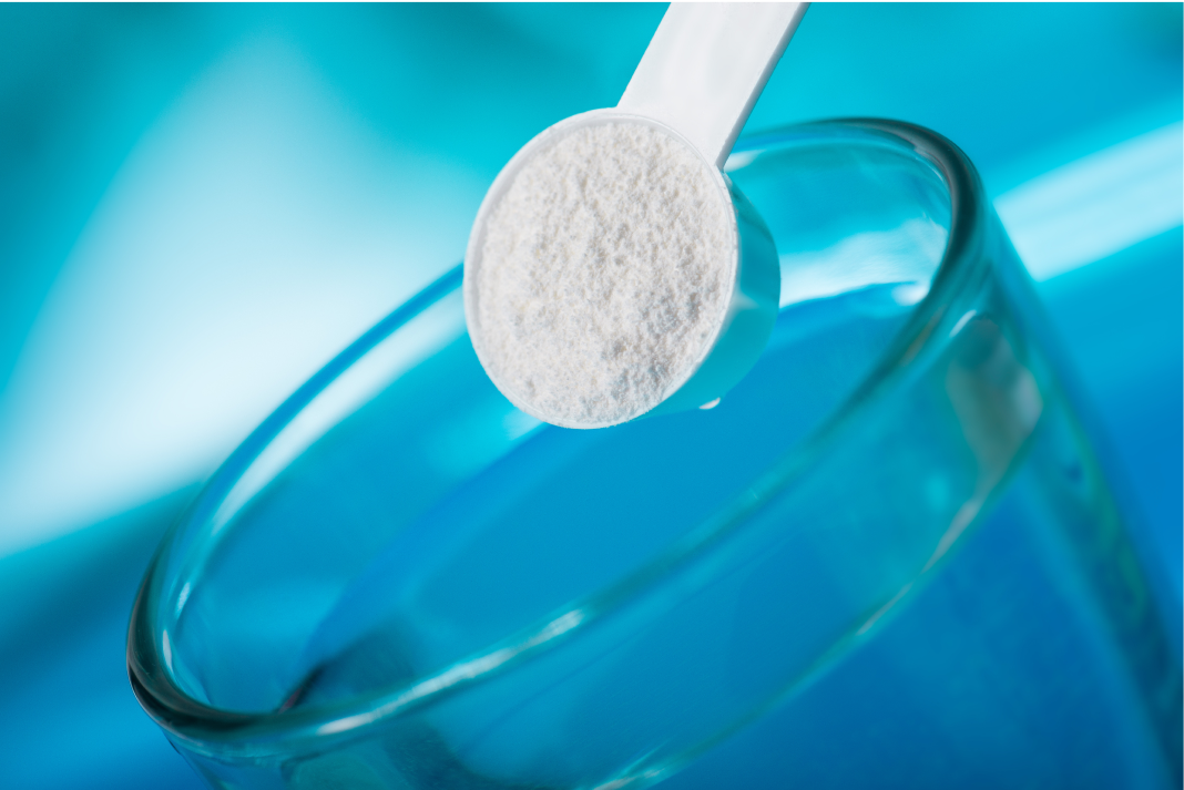 A scoop of white powder above a glass of water.