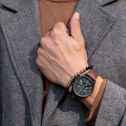 A man wearing a brown leather wristwatch. 