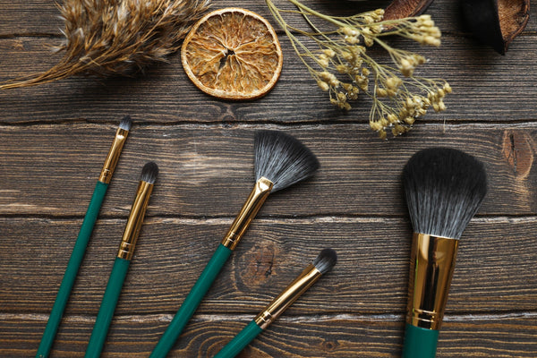 Should you mix sunscreen and foundation? An array of make up brushes with green handles atop a wooden table 