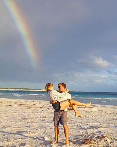 Tom holds Sacha under a rainbow in Lancelin WA