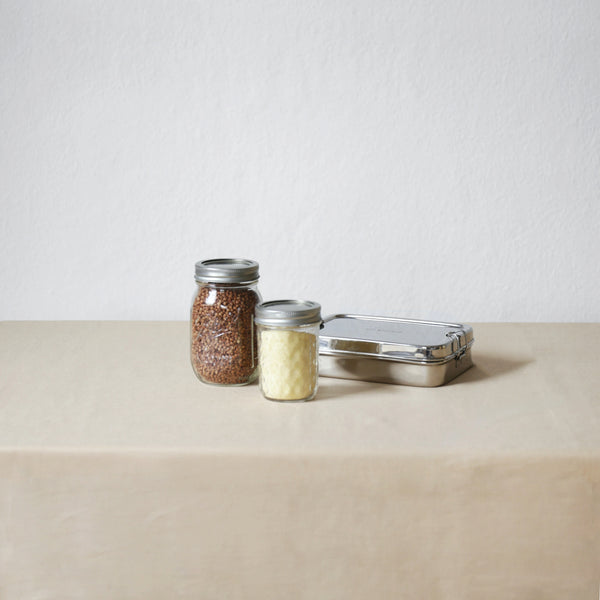 Our extra tips for Plastic Free July: An image of two jars and a bento box on a surface with a white background 