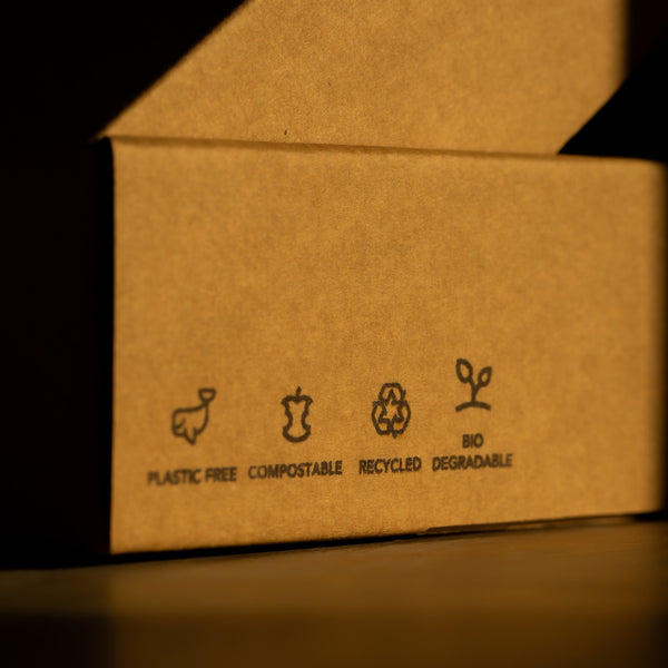 Our extra tips for Plastic Free July: A cardboard box with recycling, compostable, plastic free and biodegradable symbols on the side 