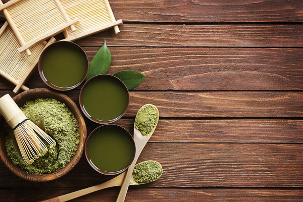 The lowdown on free radicals, antioxidants and your skin. An aerial image of traditional matcha tea powder and wooden instruments placed on a wooden table 