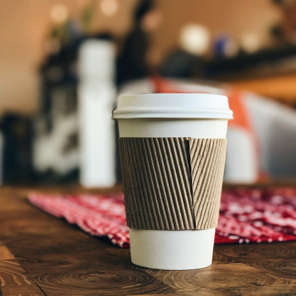 Our extra tips for Plastic Free July: A white takeaway coffee cup sits on a table 