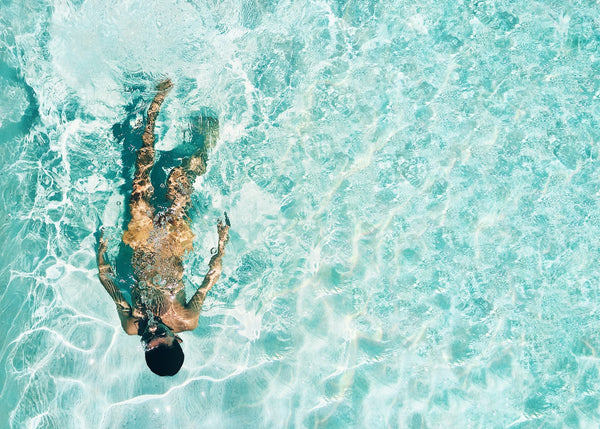 What is SPF and why is it important? Aerial image of a woman swimming in turquoise blue water