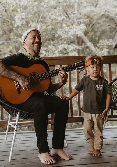 a person playing a guitar next to a boy sitting on a bench