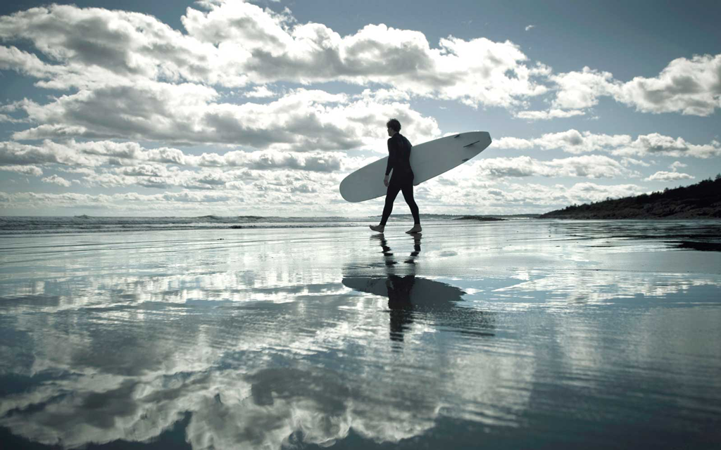 surf new england male surfer on a cloudy beach with surf board