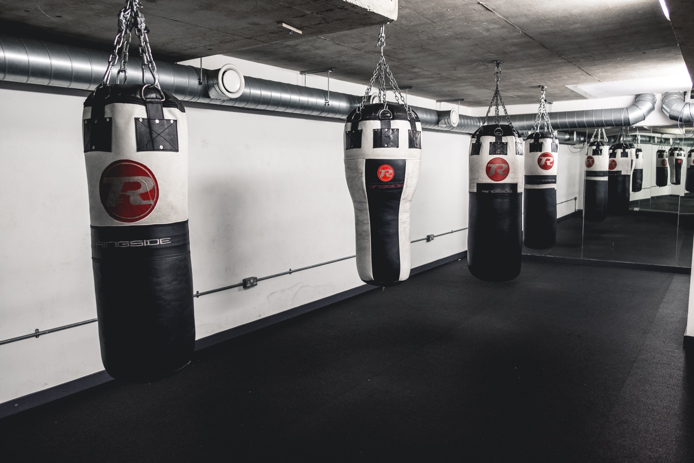 Black and white leather punchbags hanging in a gym