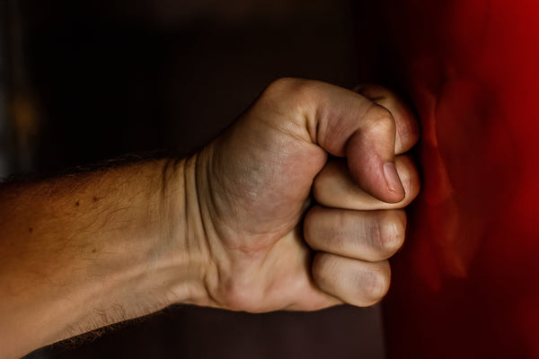 Clenched fist hitting punching bag closeup