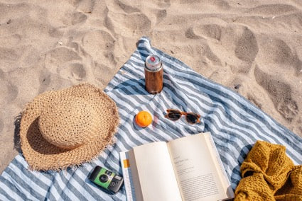 Beach towel spread out on the beach with a book