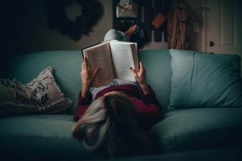 Woman lying on a couch reading a book.