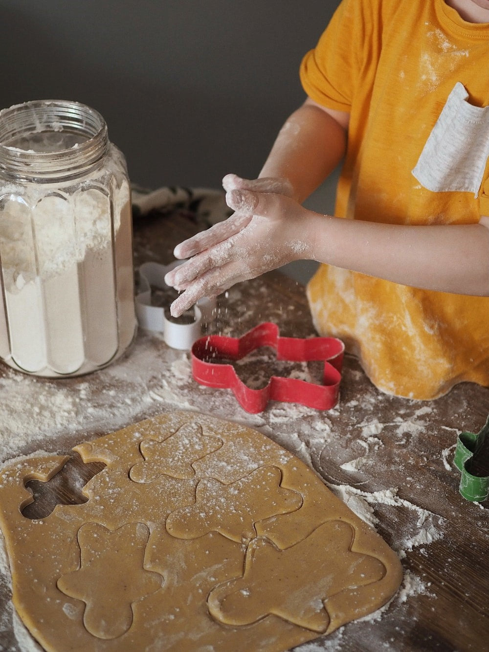 Child rubbing his hands in flour over raw cookies.