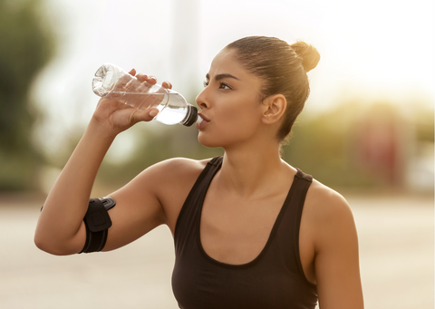 Woman wearing sportswear drinking water outdoors