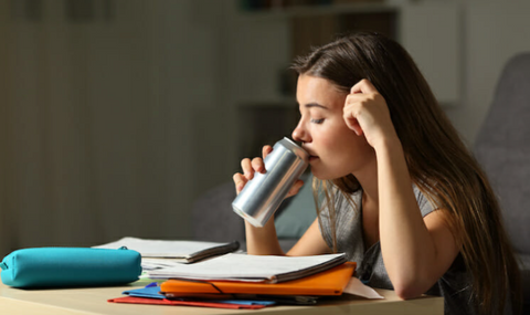 Girl drinking an energy drink while studying
