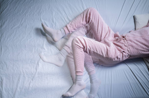 Woman lying in bed moving her legs.