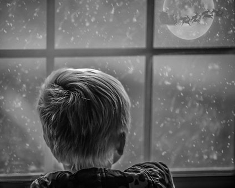 Boy looking out the window at Santa and reindeer