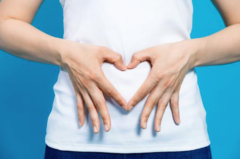 Woman with her hands on her belly in the shape of a heart