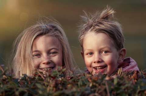 Children smiling behind bushes