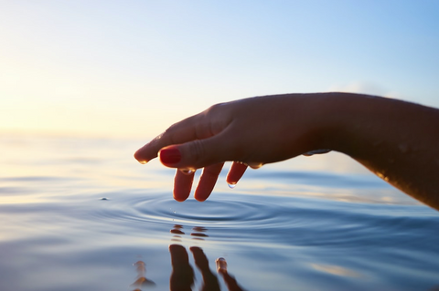 Hand touching the surface of the sea