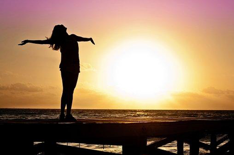 Woman with open arms next to the sea