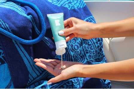 Woman putting sunscreen lotion on her hand.